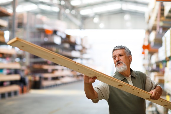 A man inspects a piece of lumber.