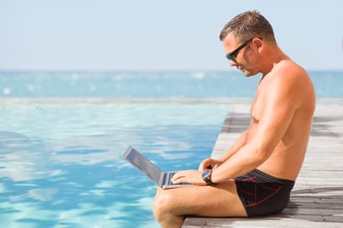 man using laptop by a pool_GettyImages-497211176