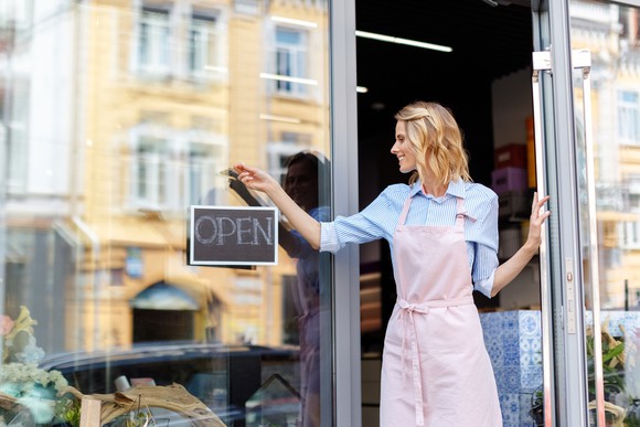 A woman hangs an open sign.