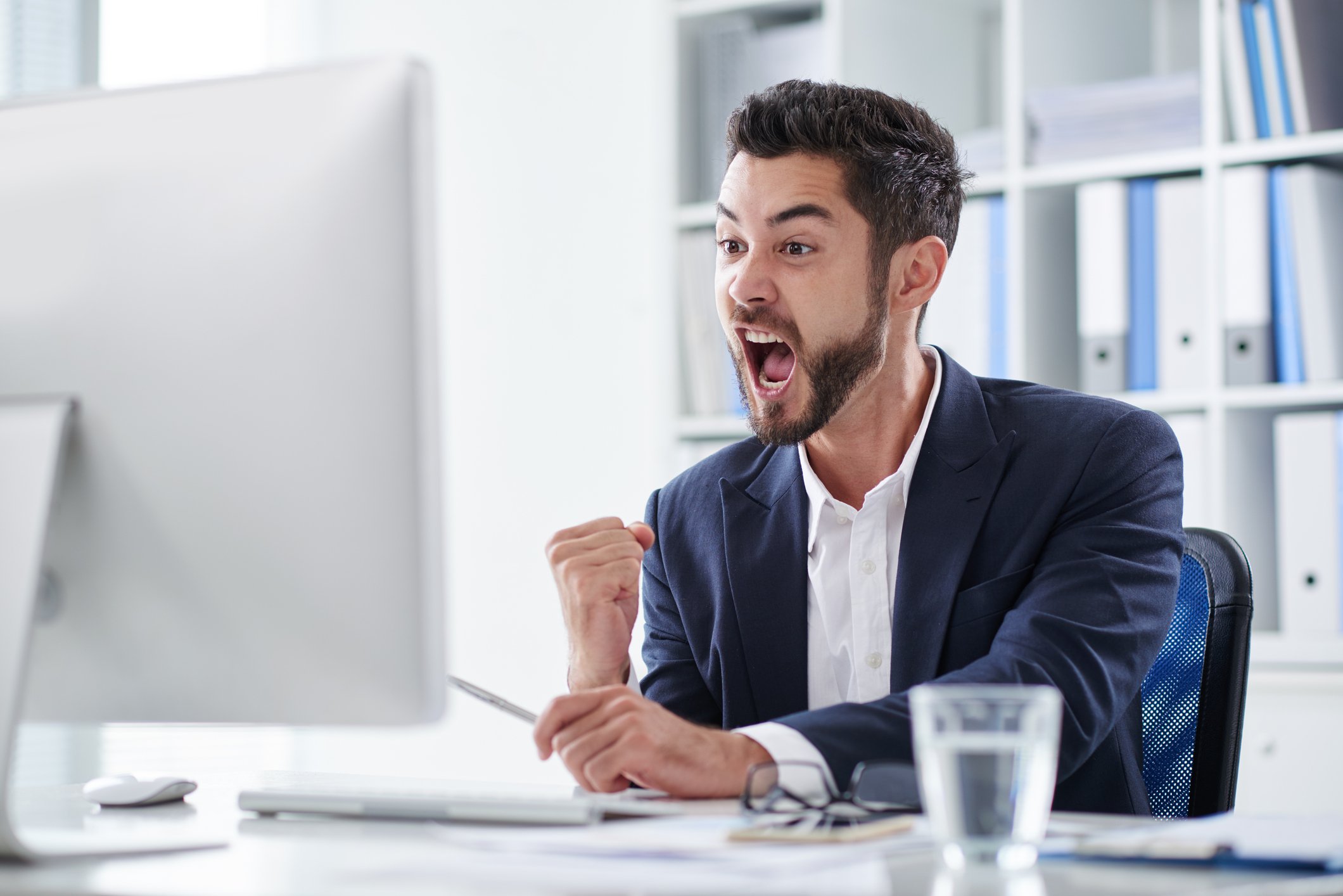Happy young man screaming of joy when looking at computer screen