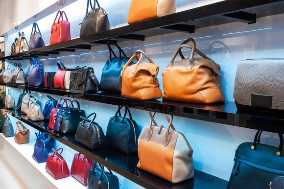 Shelves of high-end handbags in a retail store.