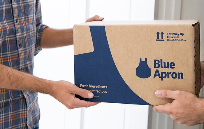 Man handing Blue Apron box to another person