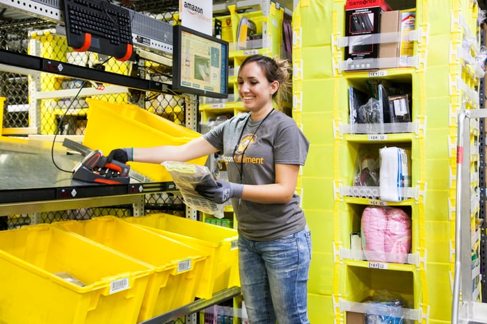 Smiling female employee scanning items at an Amazon fulfillment center