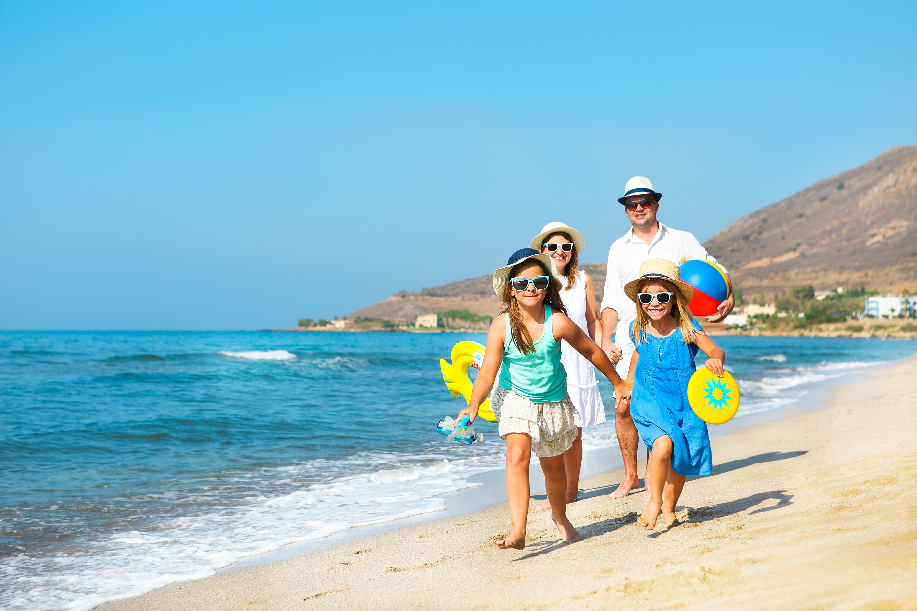 Man, woman, and two young girls walking on the beach