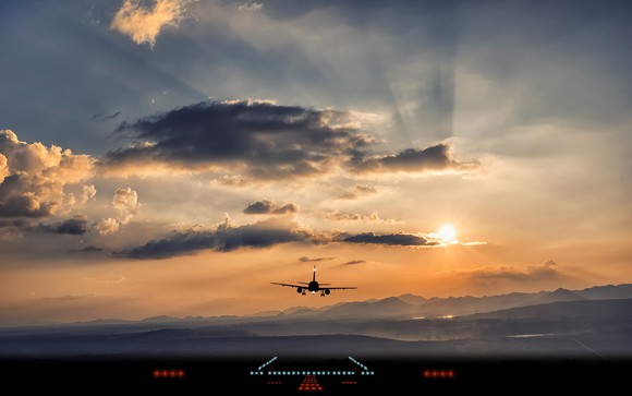 Airplane flying into setting sun
