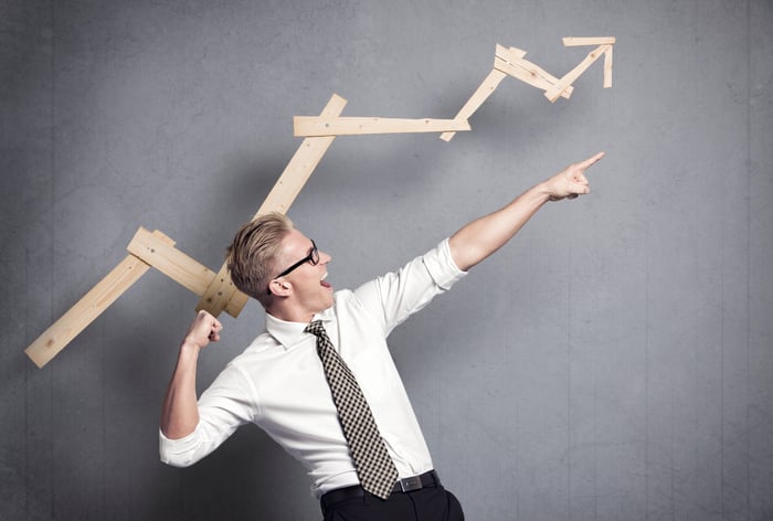 Man in white shirt and polka dot tie celebrating a chart indicating gains