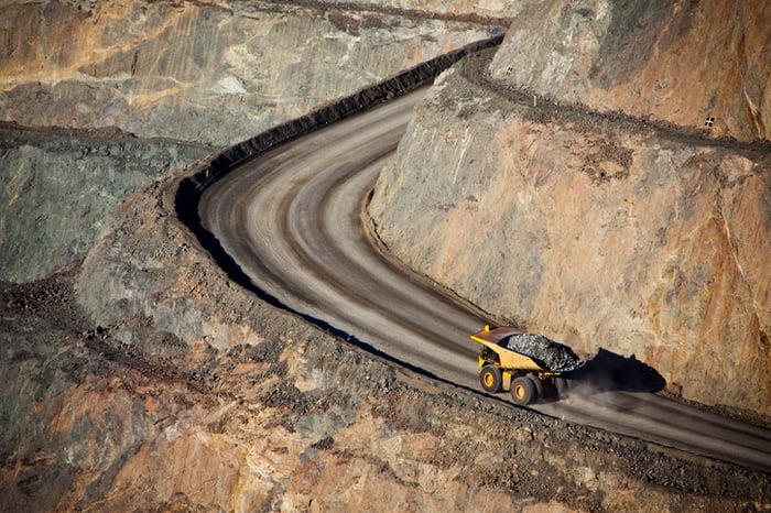 A giant earth mover driving up a road at a gold mine.