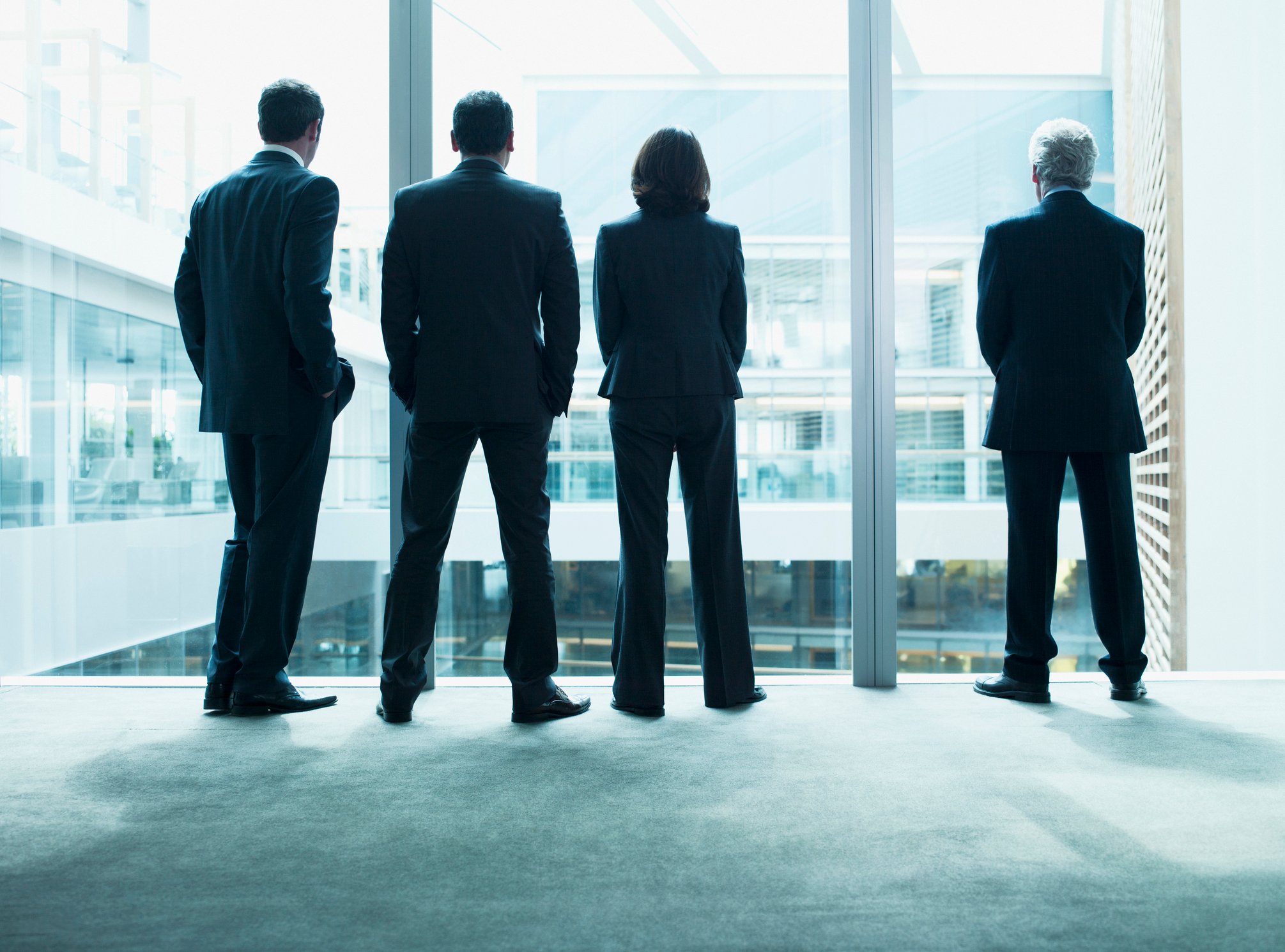 Four executives in suits staring out a window