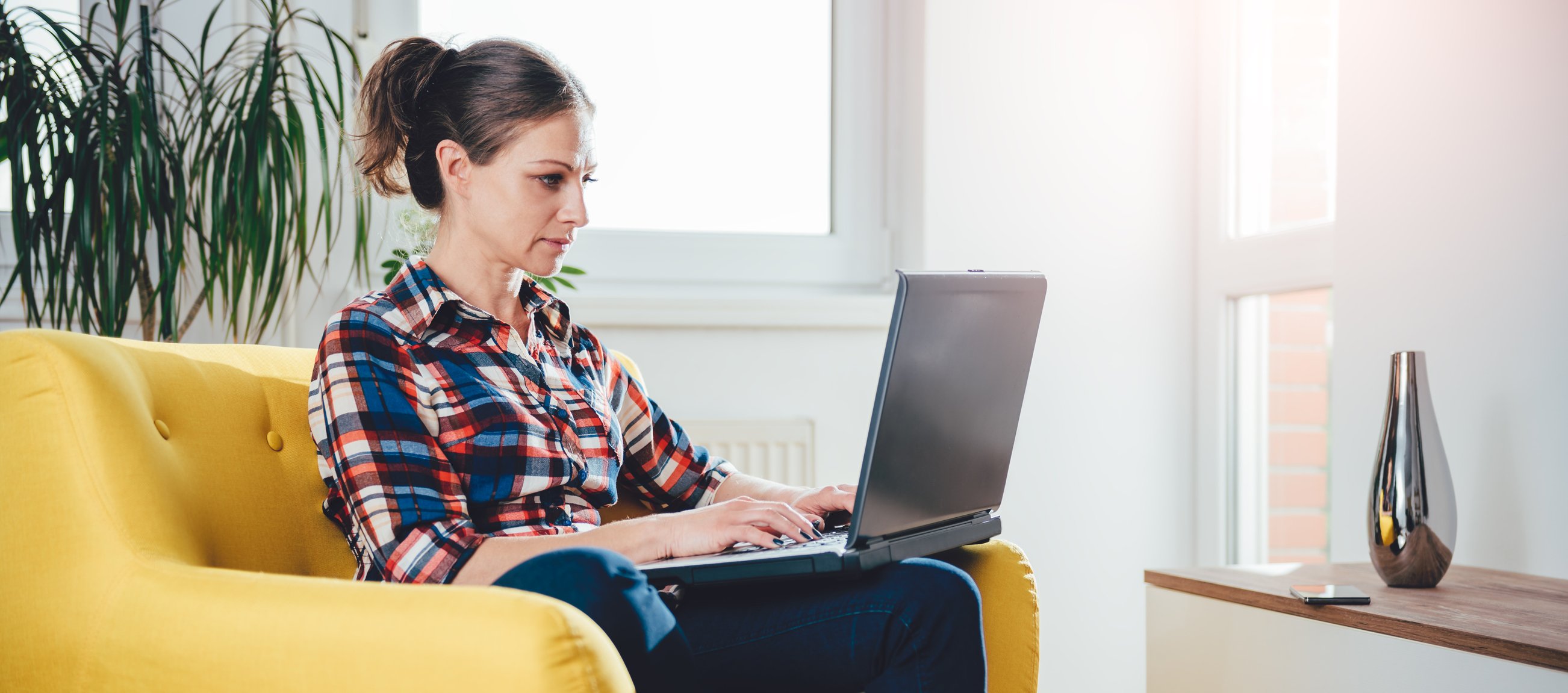 Woman typing on a laptop while sitting on a couch