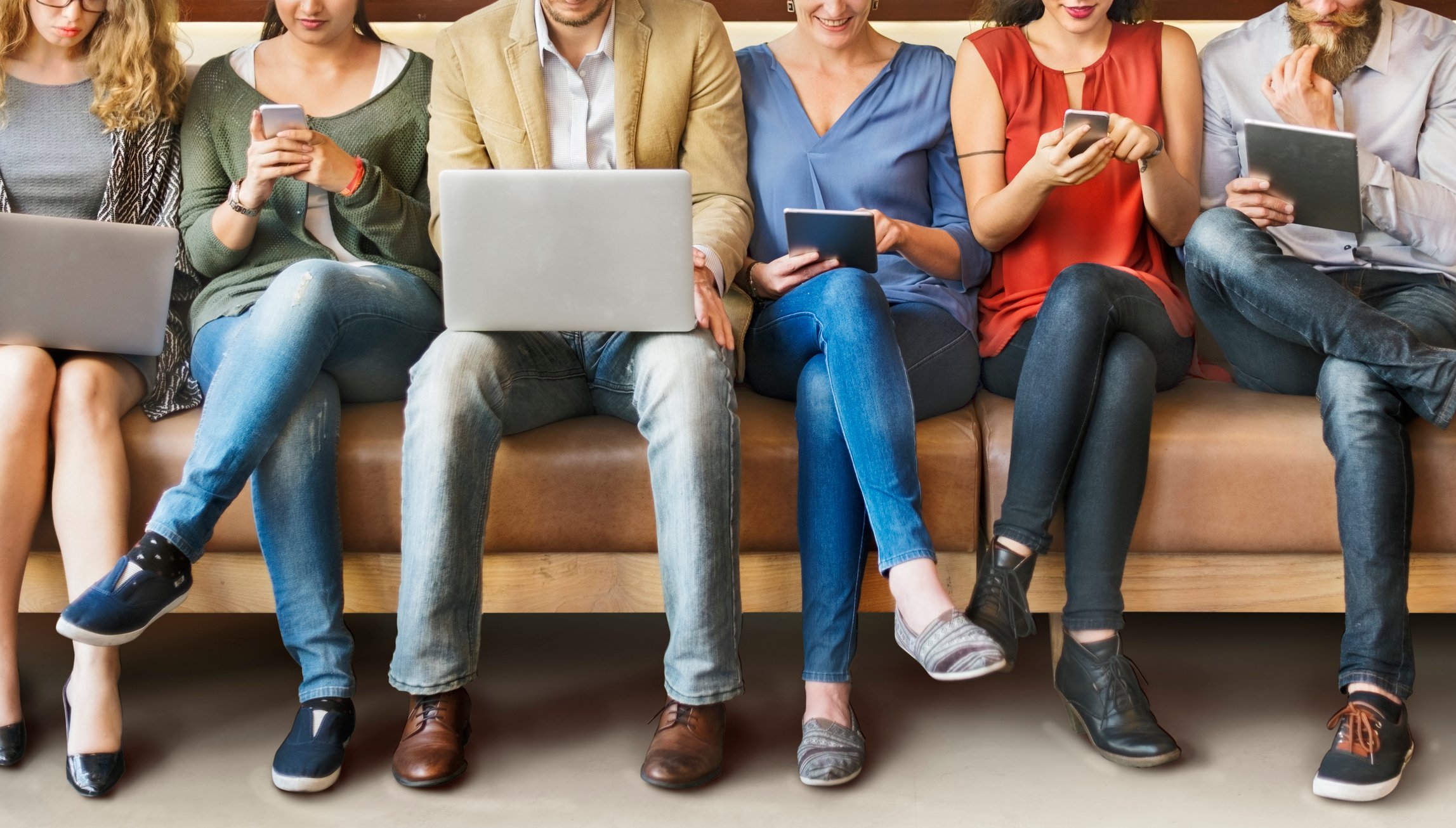 Young people sitting around using various devices. 