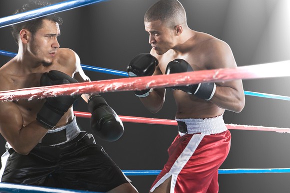 Two boxers squaring off in a boxing ring.