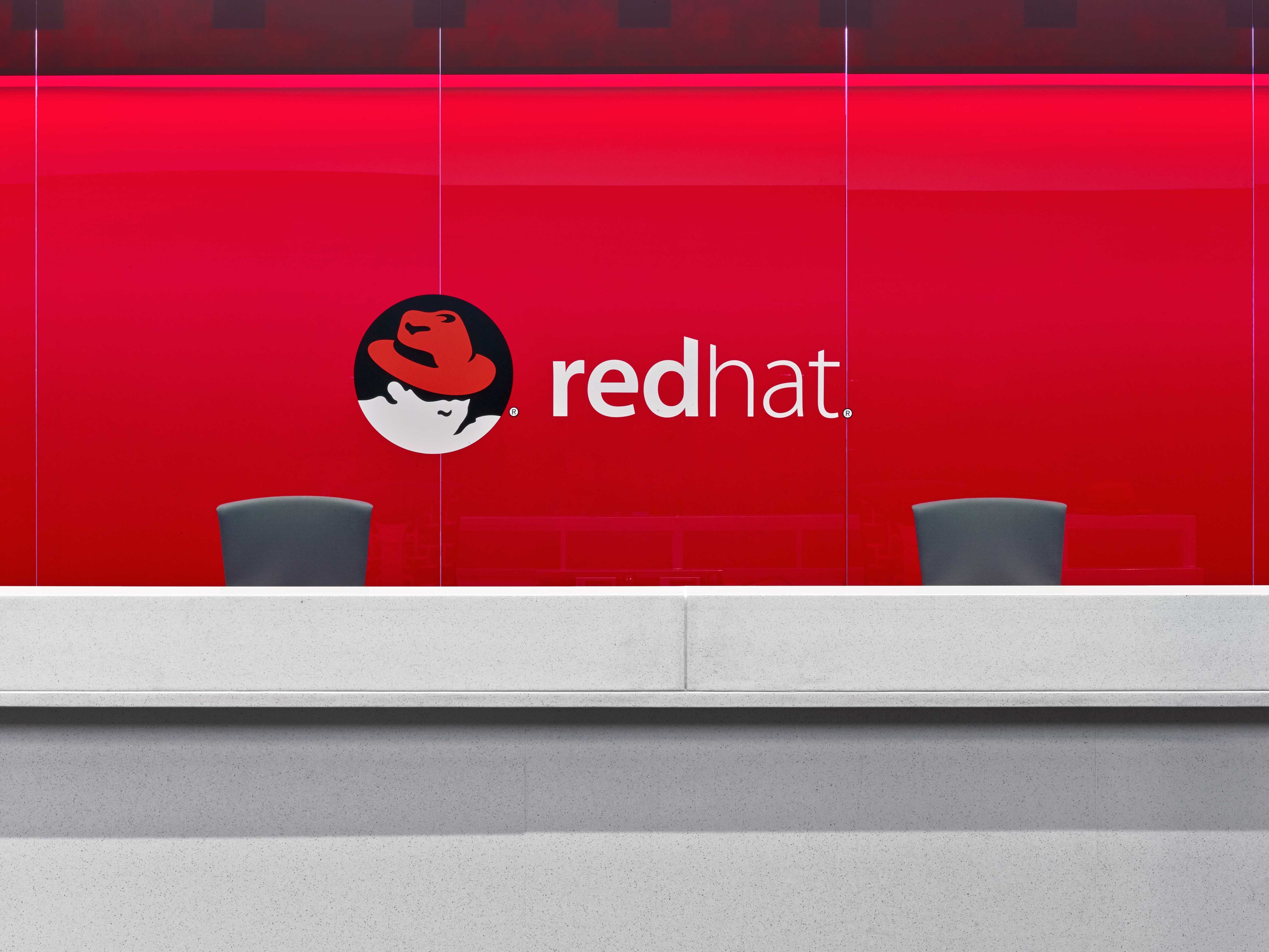 Red Hat logo on a bright red wall.