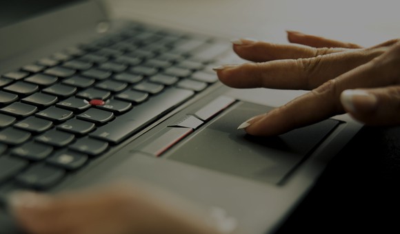 Computer keyboard with finger touching a touchpad.