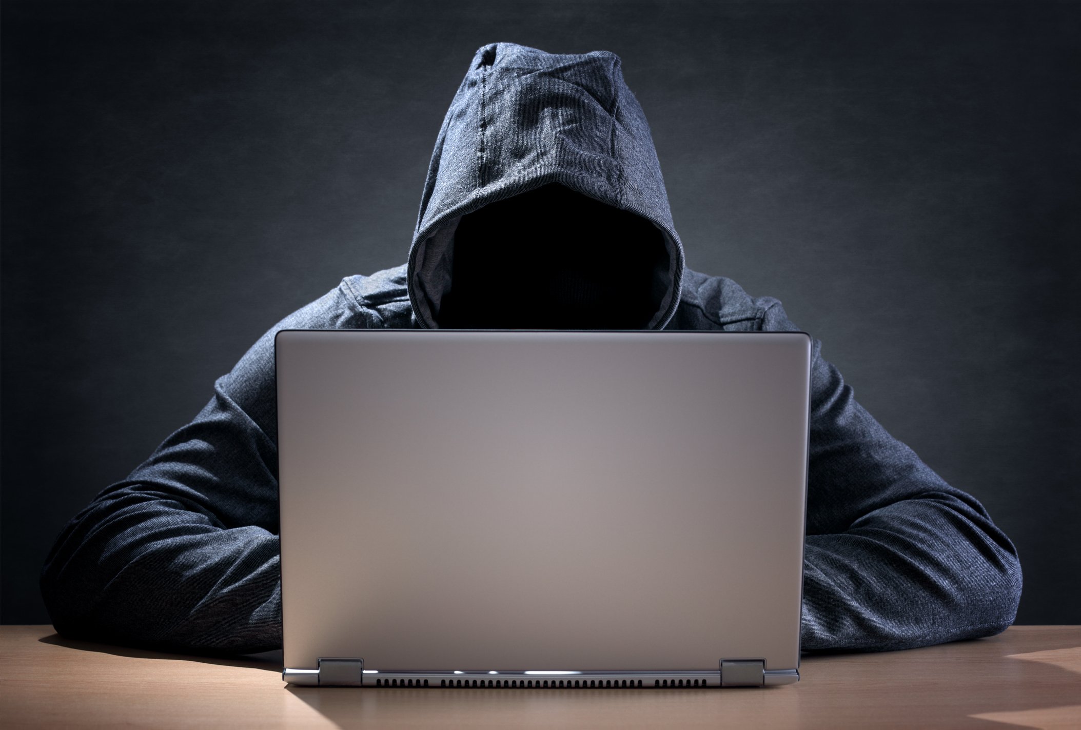 Hooded person using a laptop.