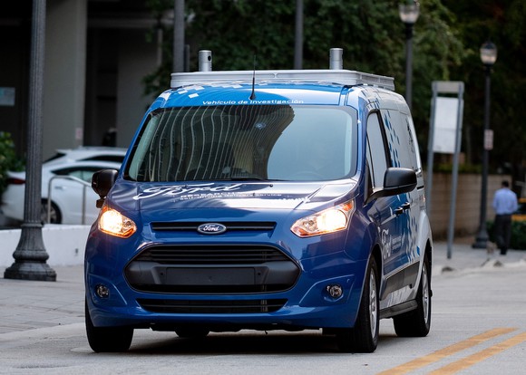 The modified Ford Transit Connect is shown from the front, with what appear to be self-driving sensors visible on the roof.