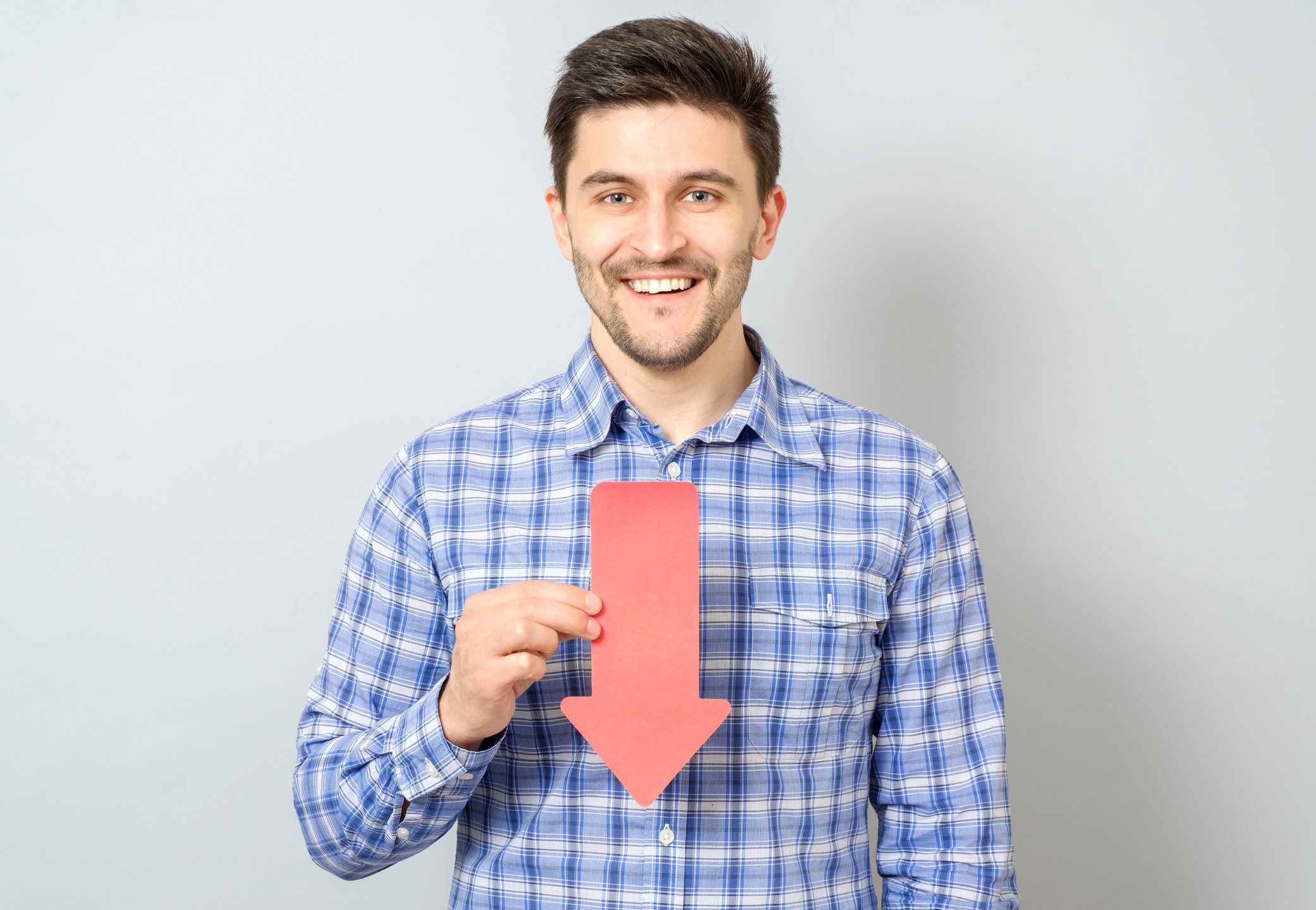 Man smiling while holding arrow that's pointing down