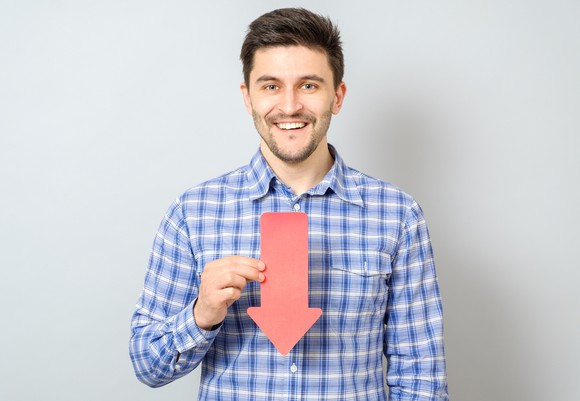 Man smiling while holding arrow that's pointing down