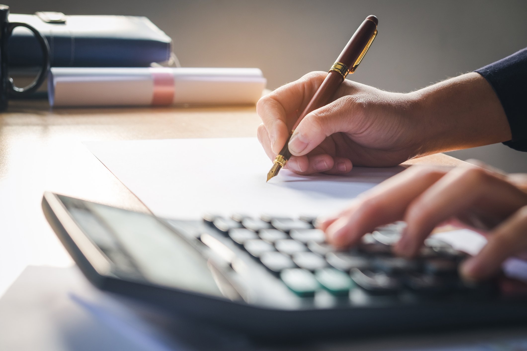 Man typing on a calculator and jotting down notes on a piece of paper