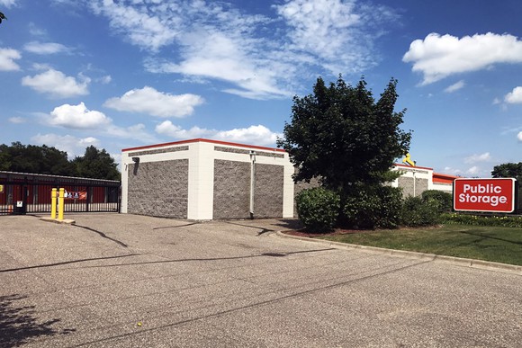 Outside of self-storage property with gate, building, and company sign.
