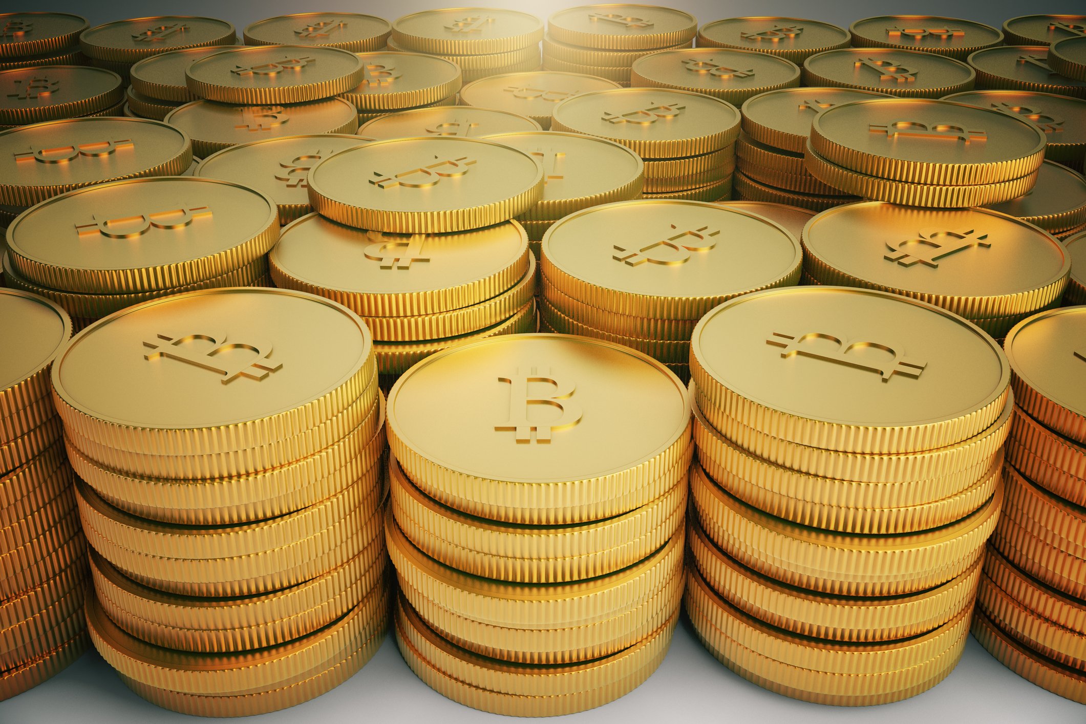 Stacks of gold coins with bitcoin symbols.