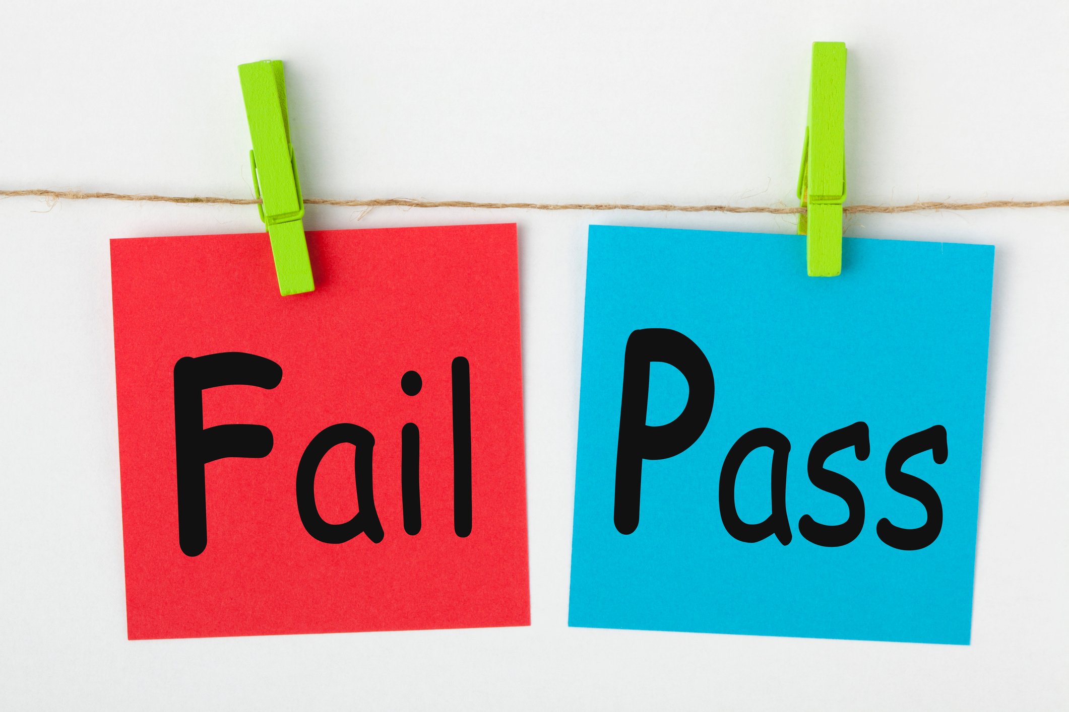 "Fail" written on red note and "pass" written on blue note with both notes clipped to a line