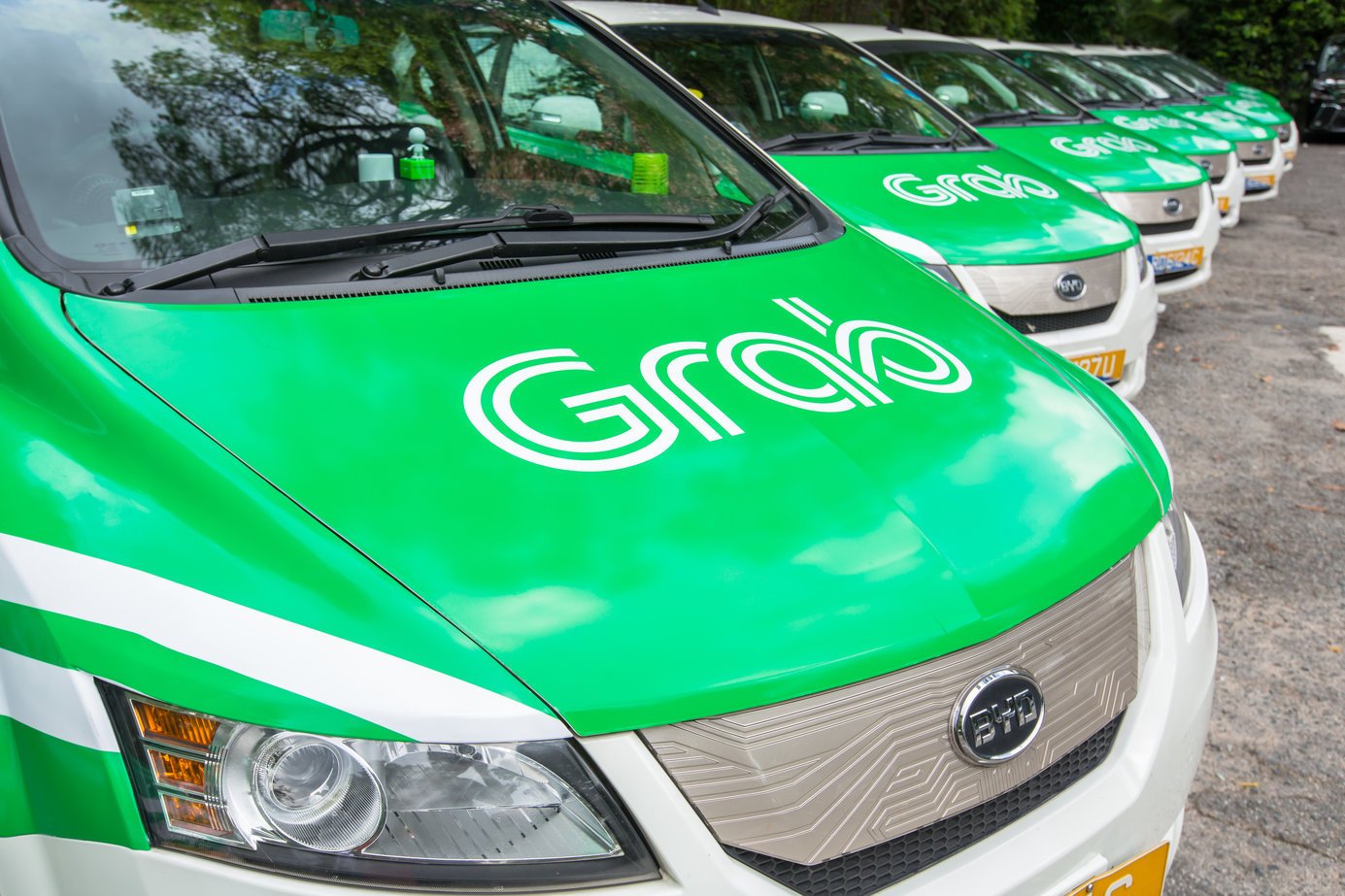 A line of small vehicles painted in Grab's green-and-white color scheme.