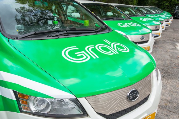 A line of small vehicles painted in Grab's green-and-white color scheme.
