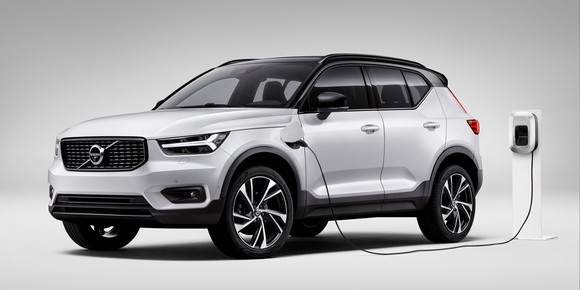 A white Volvo XC40 plug-in hybrid SUV, shown plugged into a charger.