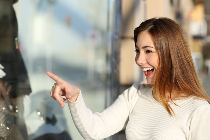 Smiling woman points at a store window.