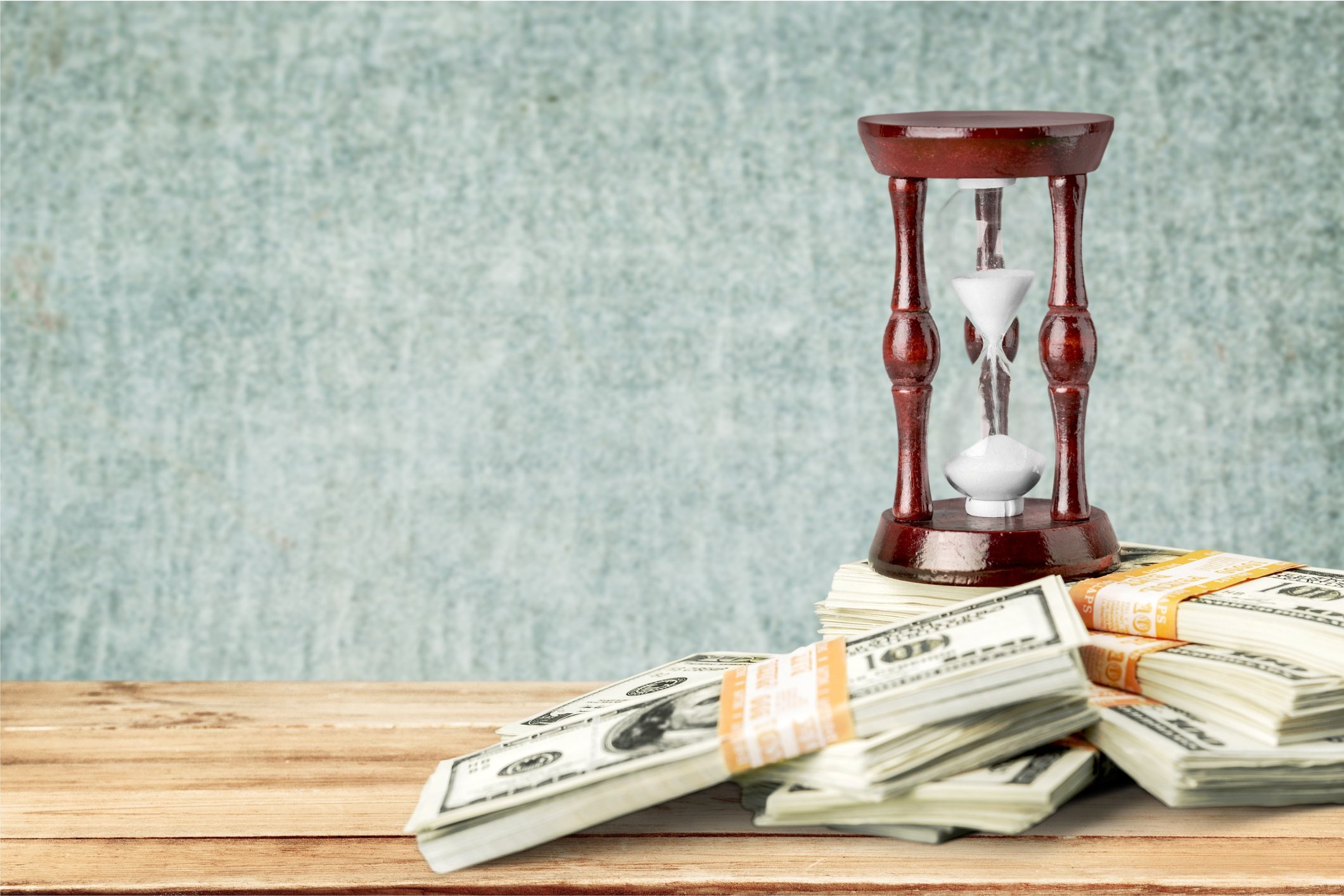 Stacks Of bills piled up near an hourglass