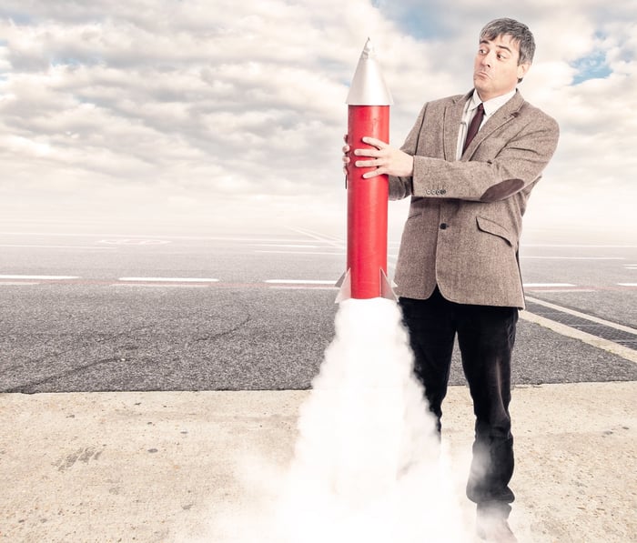 Man looks surprised as he holds a toy rocket that is starting to take off.
