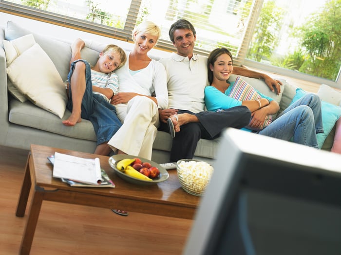 A family watches TV on the couch.