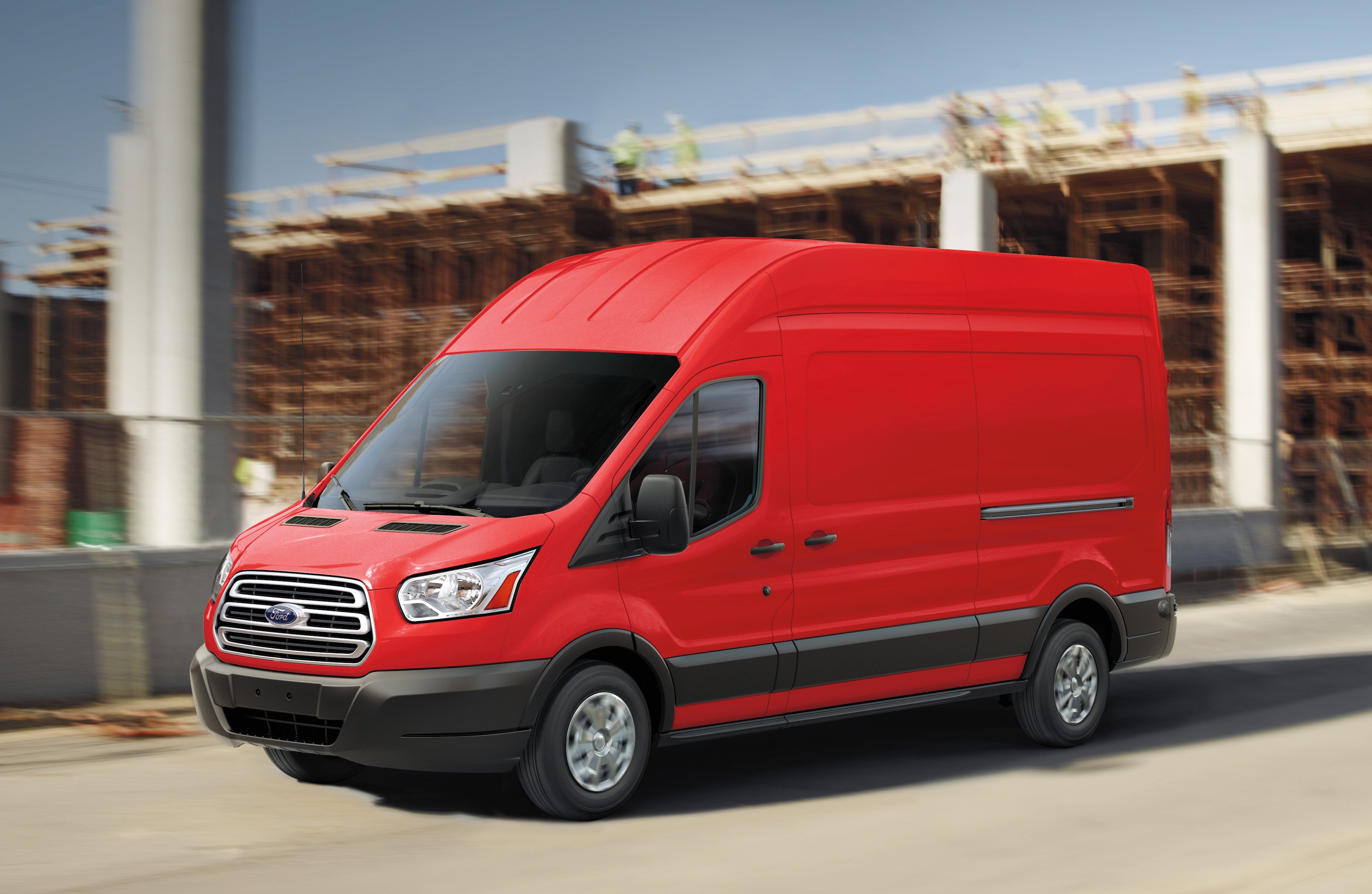 An orange Ford Transit, a commercial van that is similar in length to a large sedan, shown on a construction site.