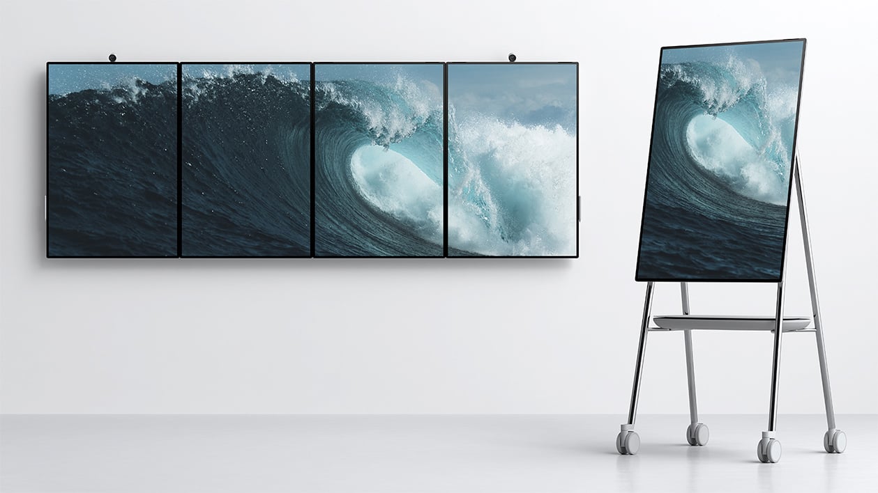 Microsoft product image of Surface Hub 2 whiteboards, mounted on walls and resting on rolling stand.