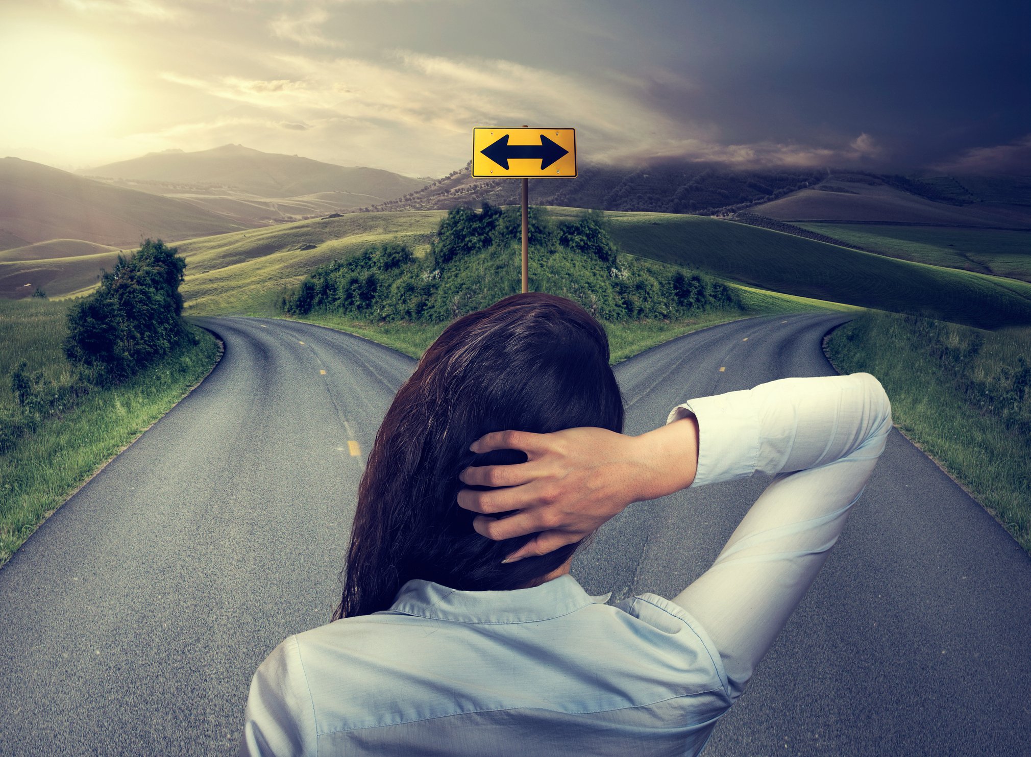 A person stands at a fork in a road.