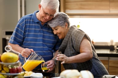 Couple in their 70s pouring OJ