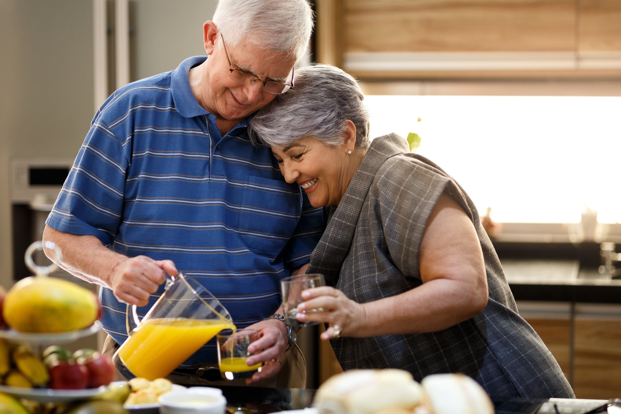 Couple in their 70s pouring OJ