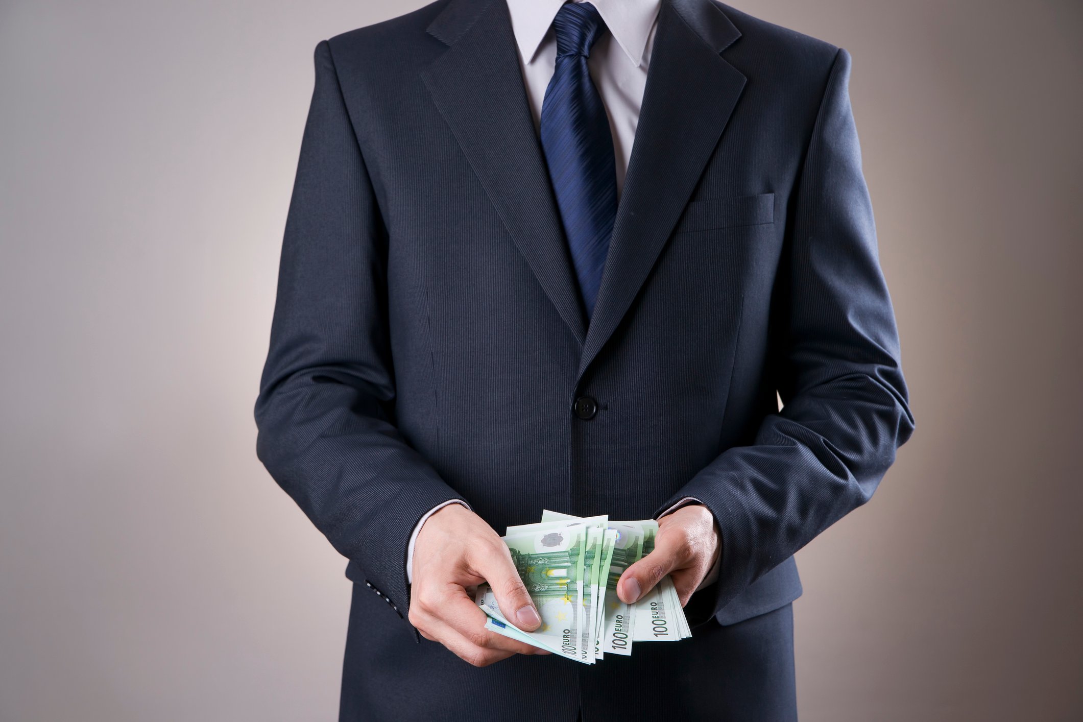 businessman holding wad of bills