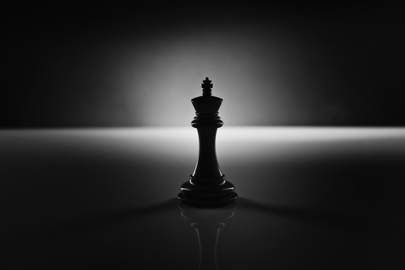A black king chess piece in the shadows.