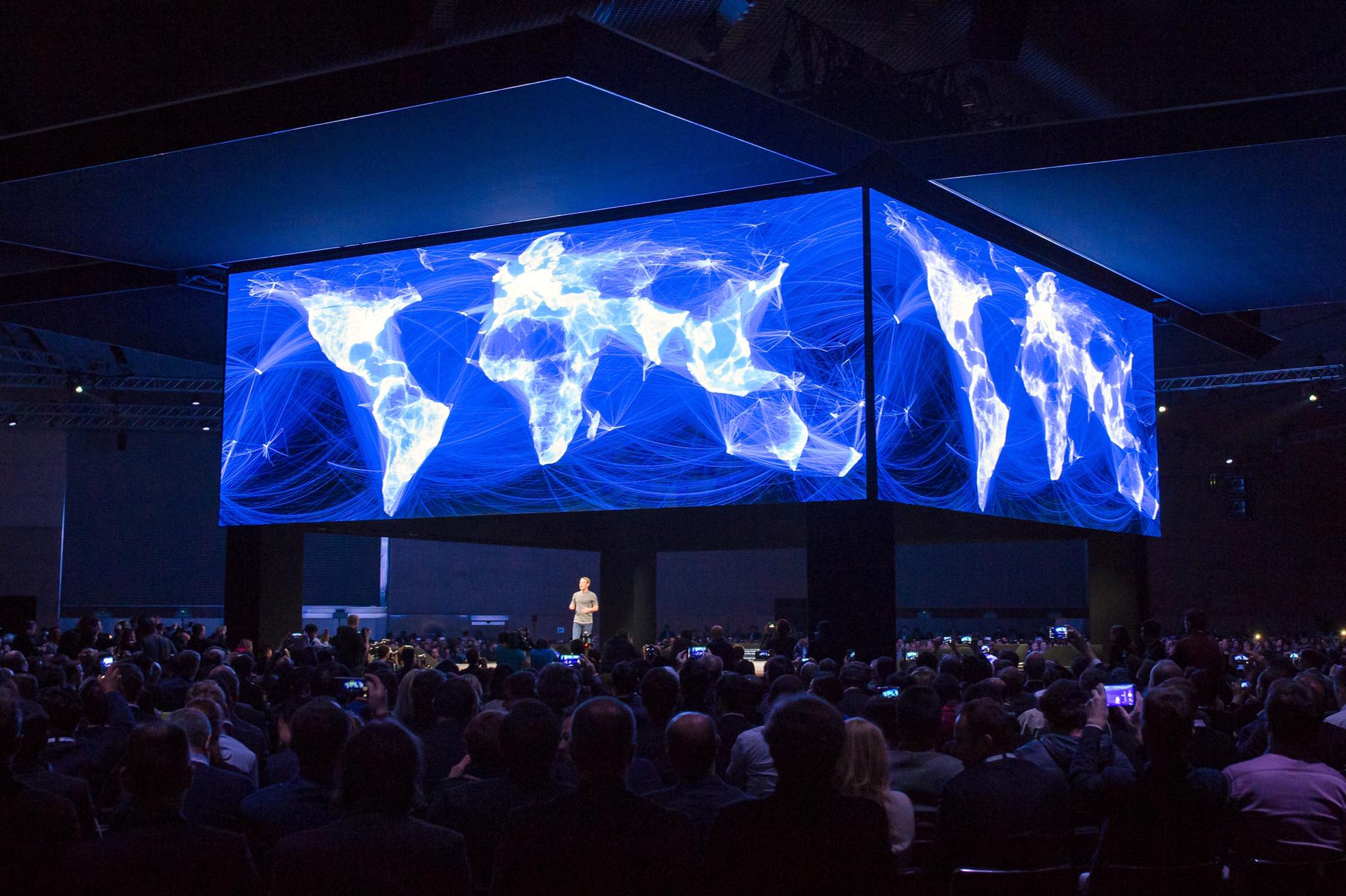 Mark Zuckerberg on stage beneath Facebook's visualization of a connected world