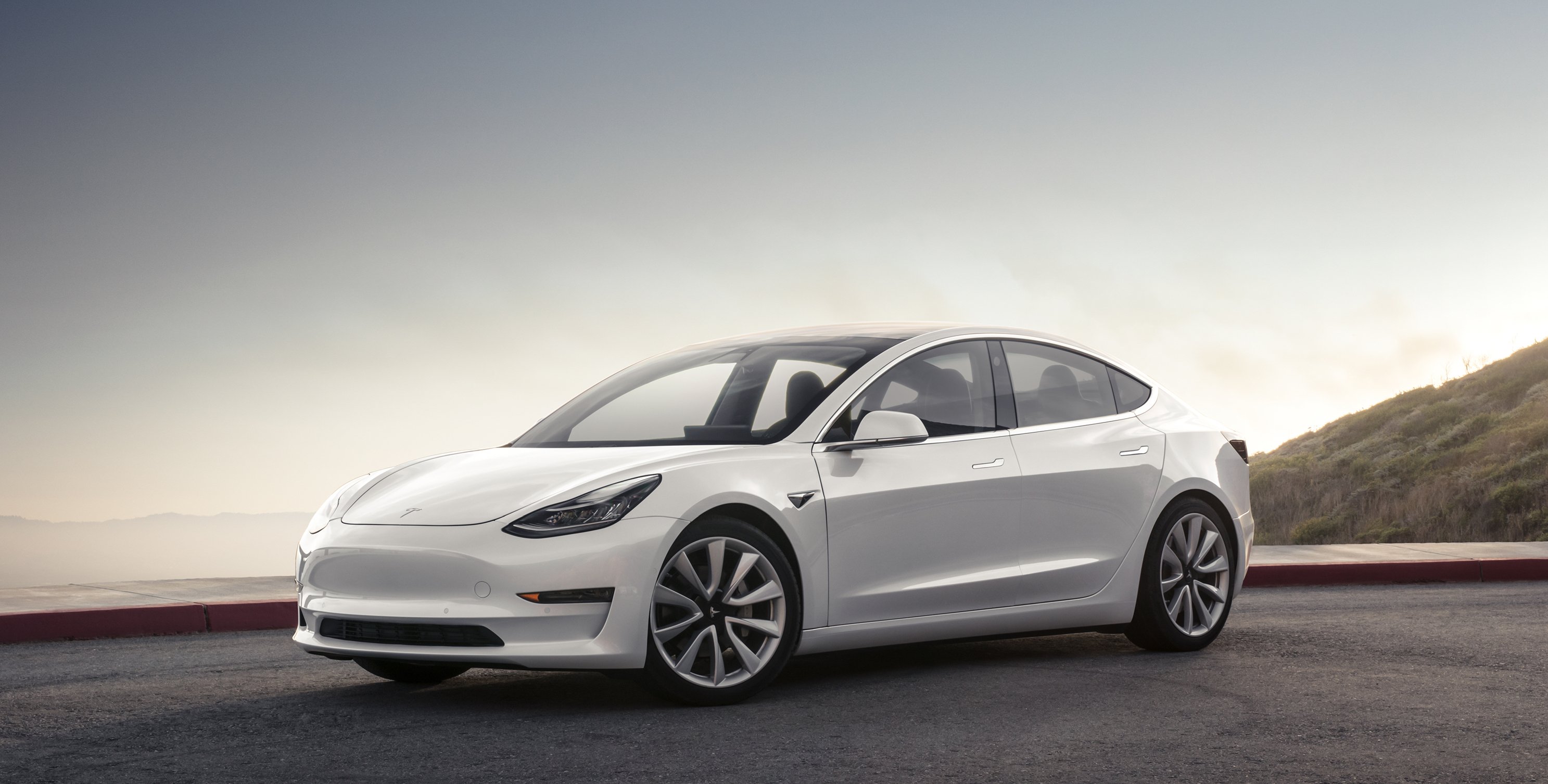 A white Tesla Model 3, a sleek compact luxury sports sedan.