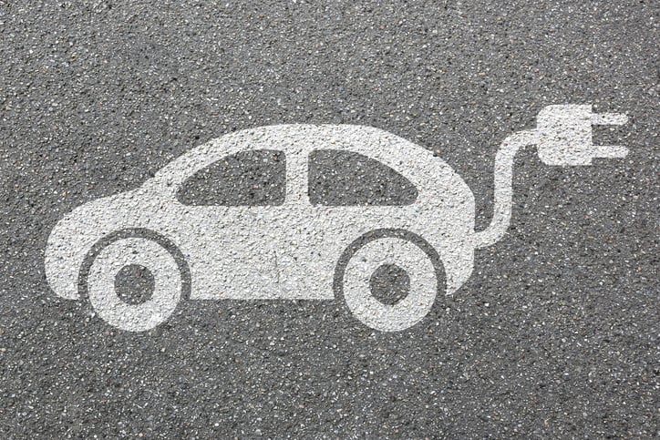 A drawing on the pavement of a car with a plug sticking out the back end.