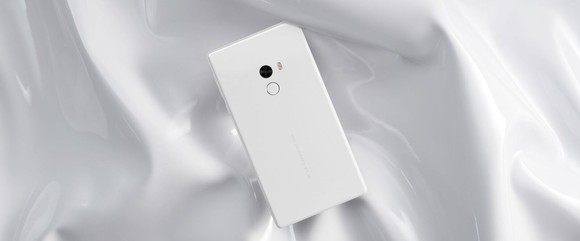 A white Xiaomi phone against a white satin background