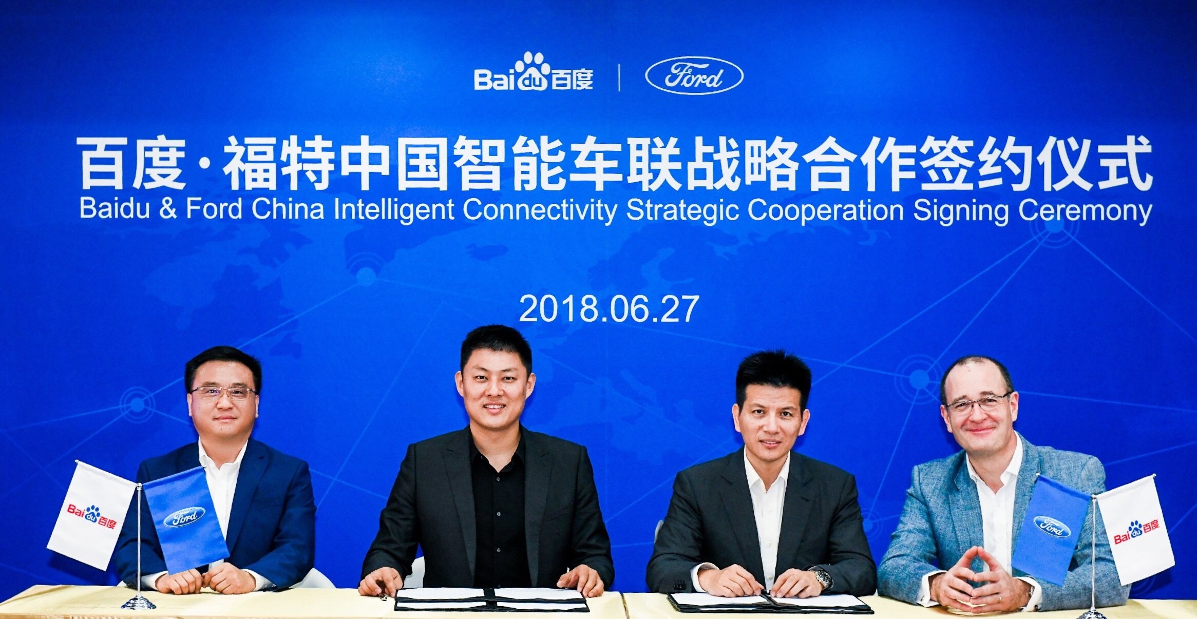 The four executives are seated at a table in front of a blue banner with the Baidu and Ford logos. 