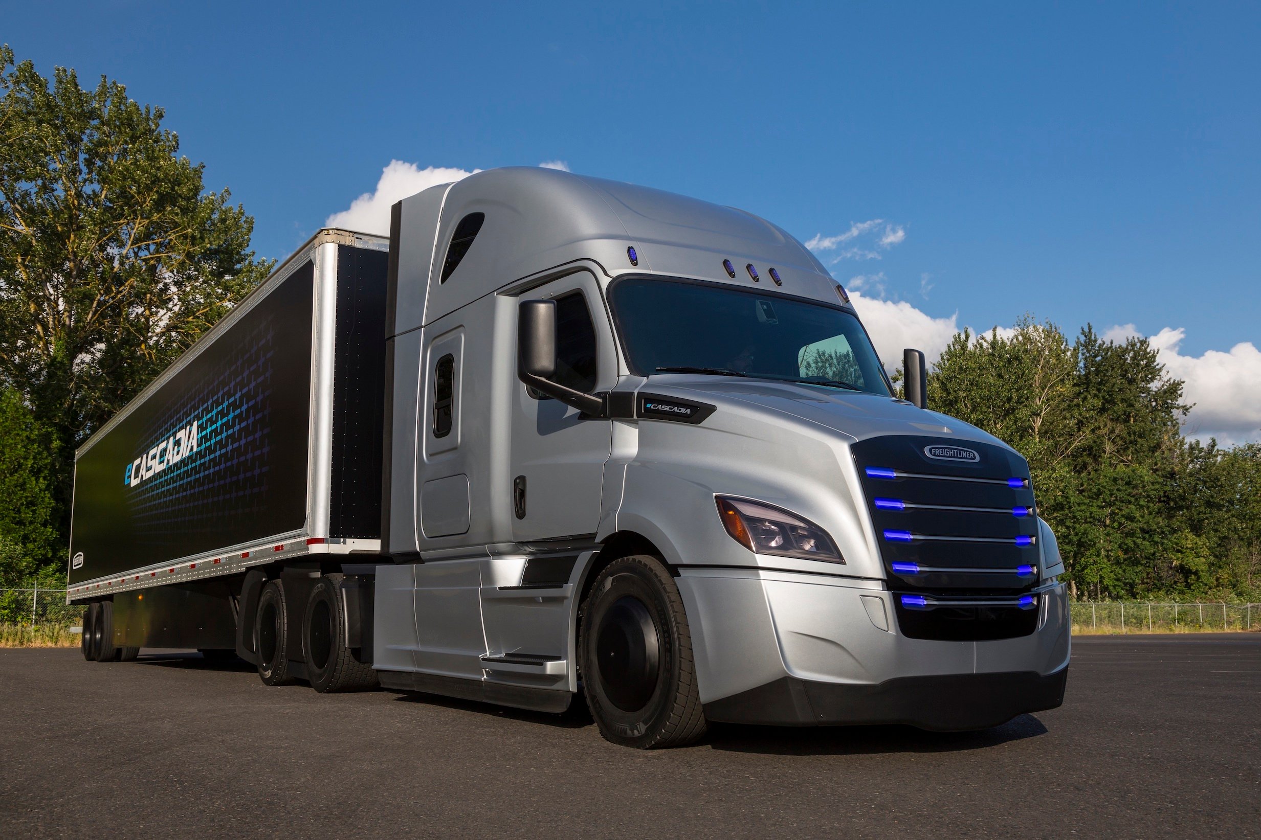 The Freightliner eCascadia, a sleek silver tractor-trailer with blue lights in its grille.