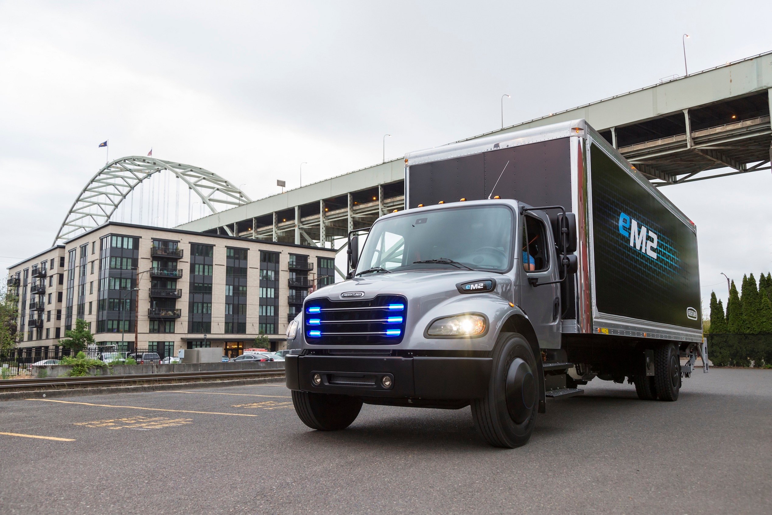 The Freightliner eM2 106, a battery-electric box truck with blue lights in its grille.