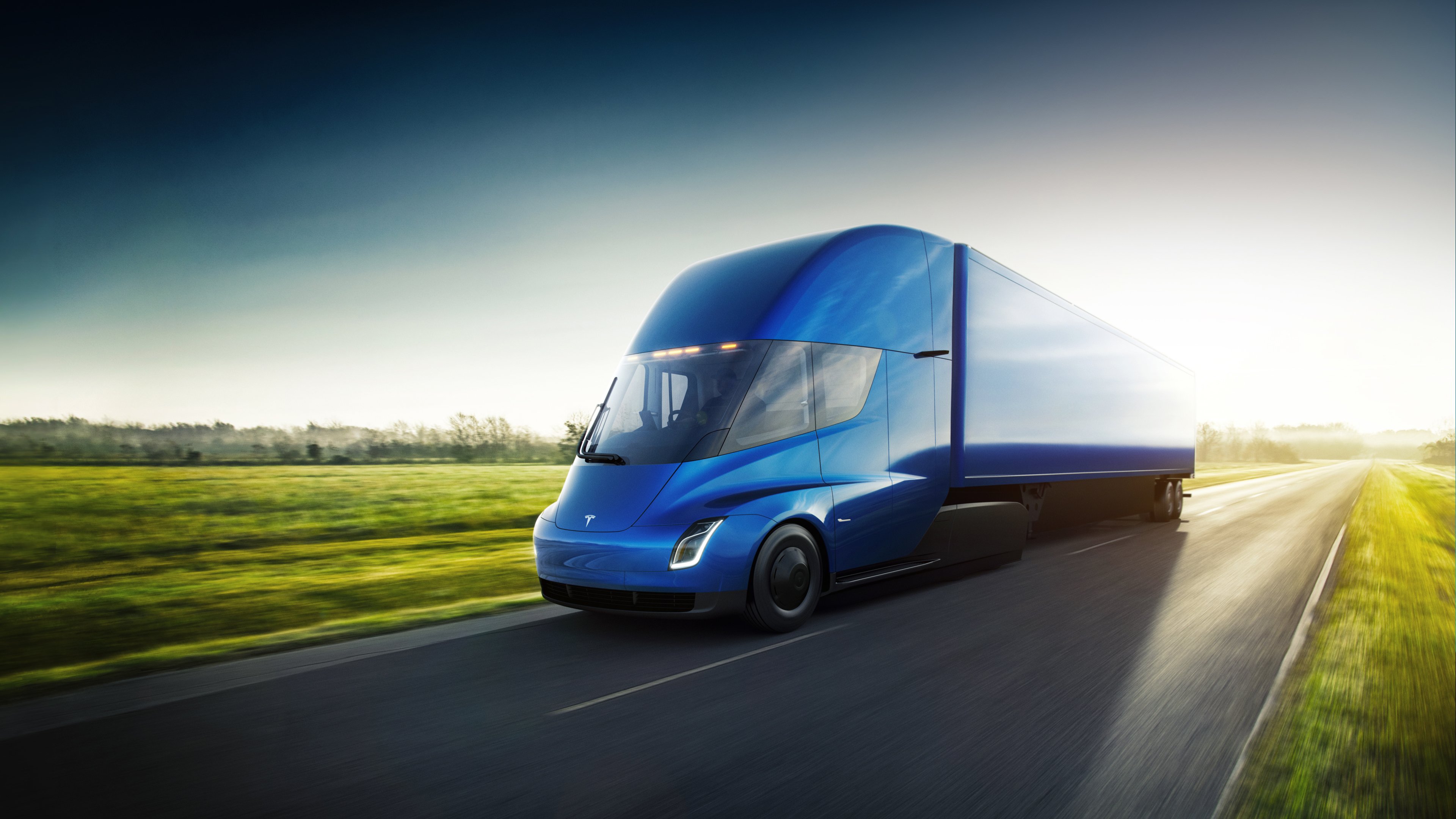 A Tesla Semi, a blue tractor-trailer truck, on a rural road.