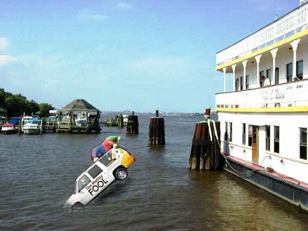 SUV with "The Motley Fool" emblazoned on the side sinking into a body of water. White building to the right, blue skies.