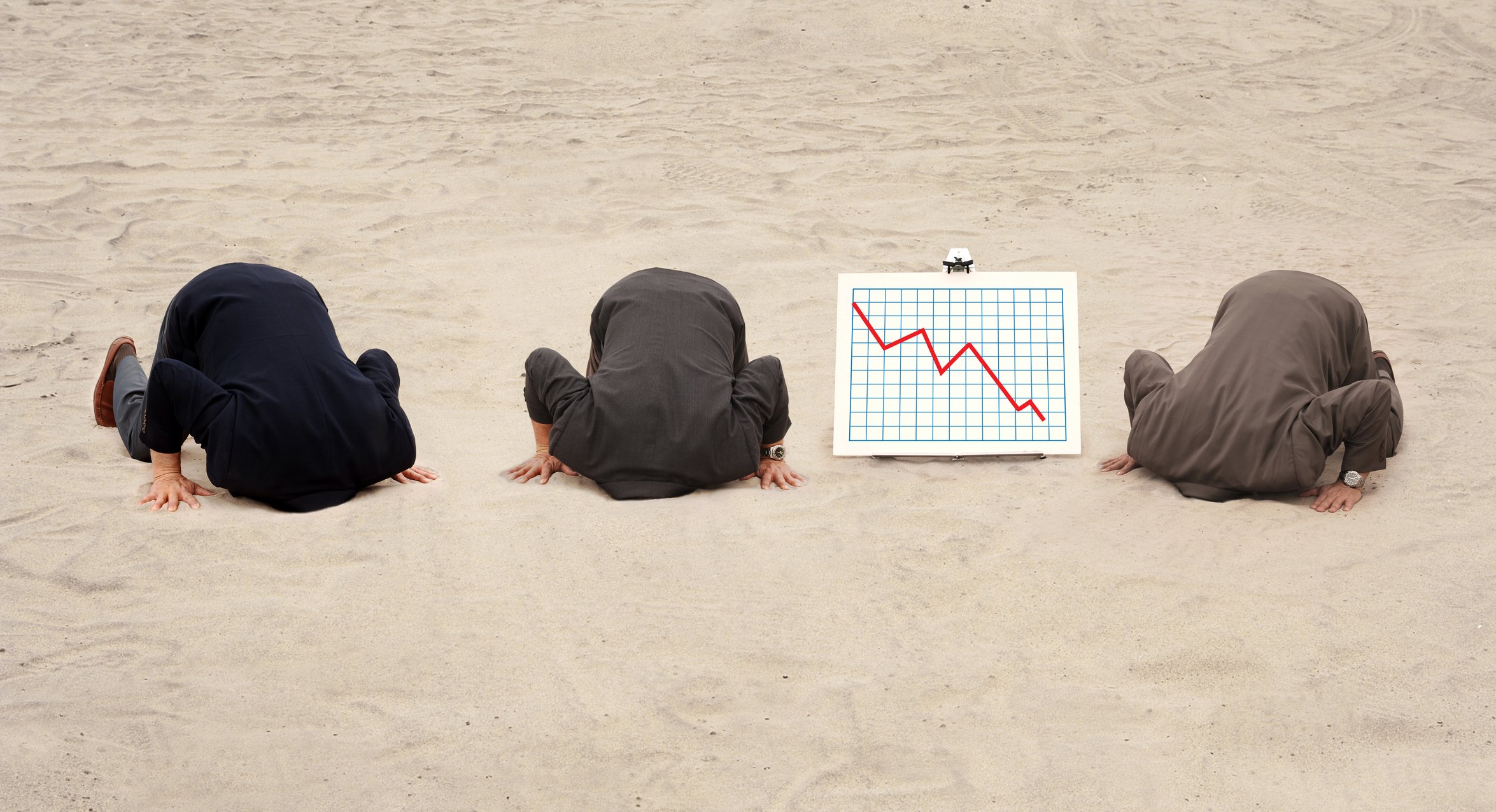 Three businessmen with their heads in the sand and a line chart trending downward