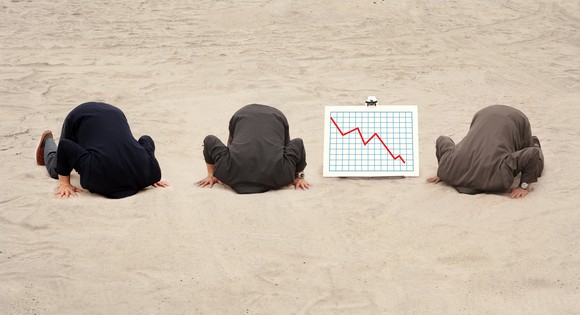 Three businessmen with their heads in the sand and a line chart trending downward